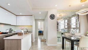Una cocina moderna con armarios blancos, una isla central y un comedor con mesa y sillas de vidrio.