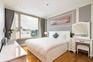 Une chambre d’hôtel avec un grand lit, un bureau et une fenêtre avec des rideaux.