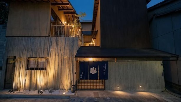 Un edificio moderno con techo plano, terraza de madera y una puerta japonesa tradicional.