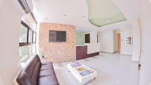 A modern living room with a sofa, coffee table, and a TV mounted on a brick wall. - Emerald Suites CDO (Cagayan De Oro)