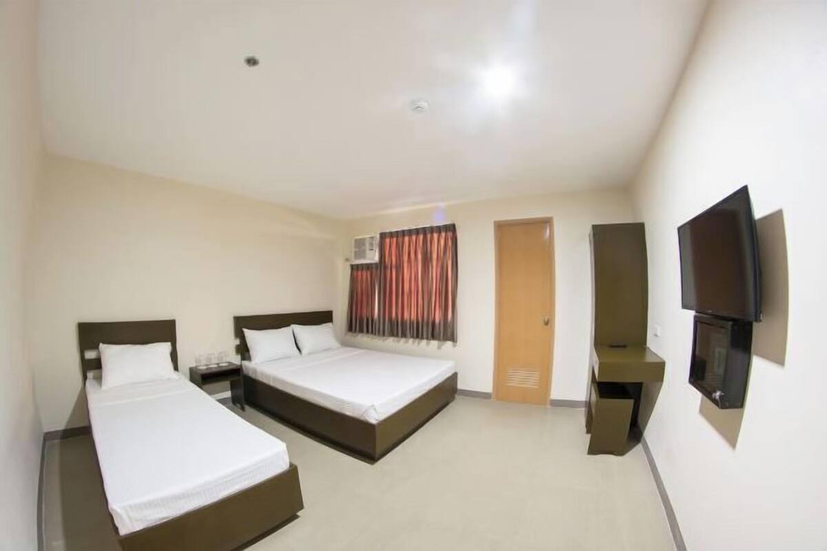A hotel room with two beds, a TV, a desk, and a wardrobe.