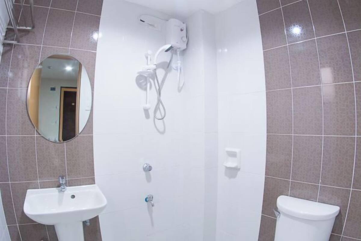 A bathroom with a sink, mirror, shower, and toilet.