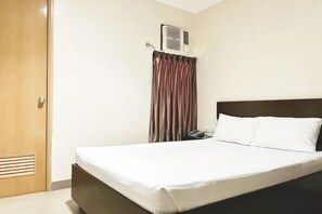 Ein Hotelzimmer mit Bett, Tür, Vorhang und Klimaanlage.
