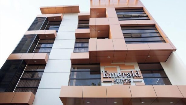 A modern hotel with a prominent 'Emerald Suites' sign, featuring a unique geometric facade with multiple balconies. - Emerald Suites CDO (Cagayan De Oro)