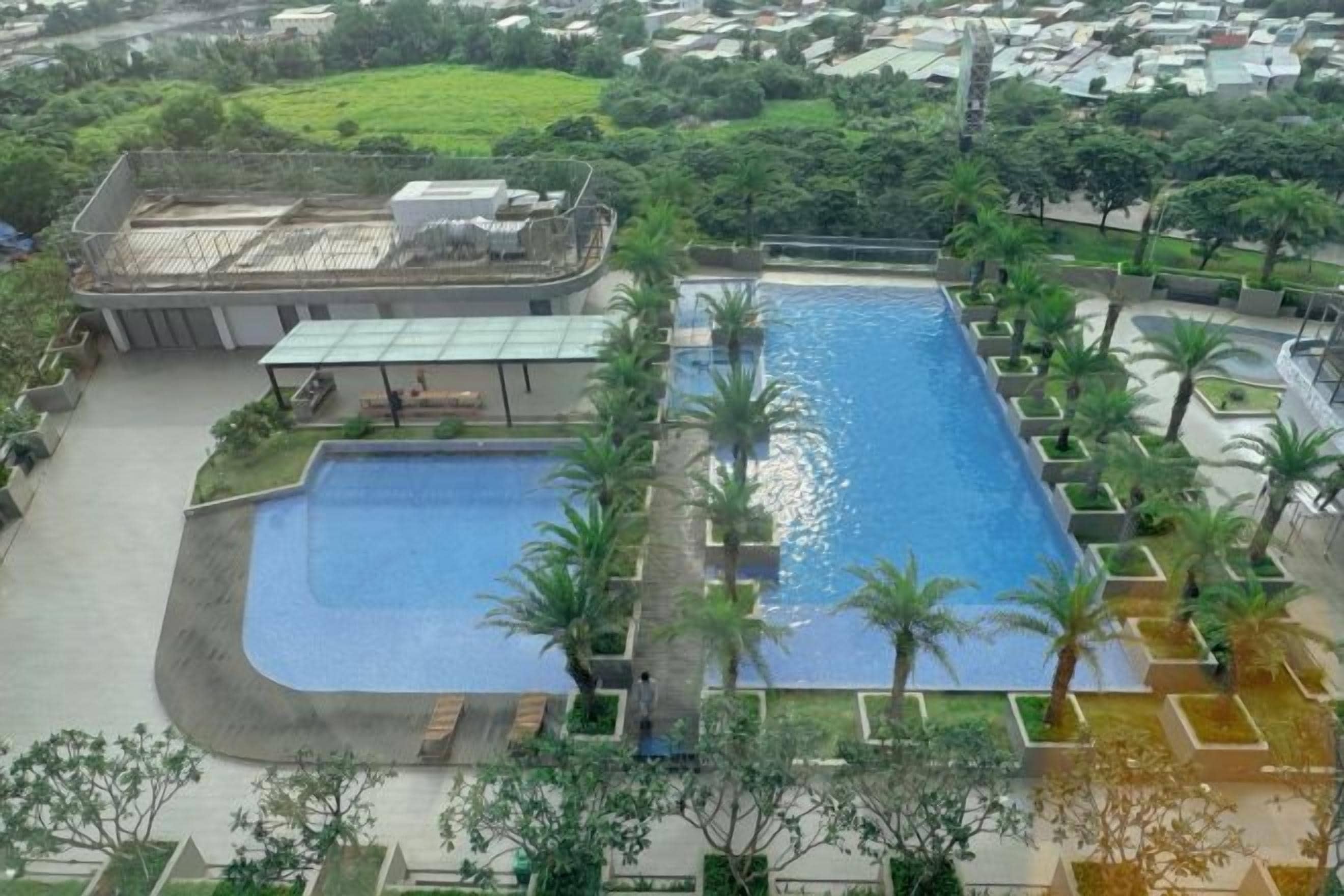 Ein großer Pool, umgeben von Palmen und einem Gebäude mit flachem Dach.