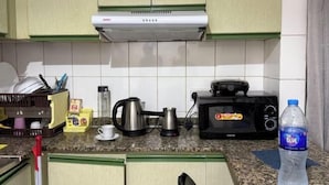 A kitchen with a microwave, toaster, kettle, and a water bottle on the counter. - Rovers Hostel (Dubai)