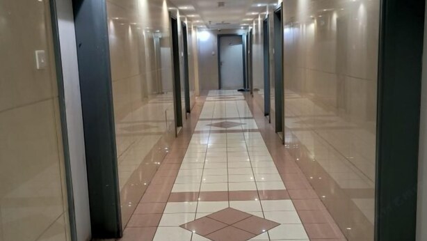 A long, well-lit hallway with tiled floors and glass doors on both sides. - Rovers Hostel (Dubai)