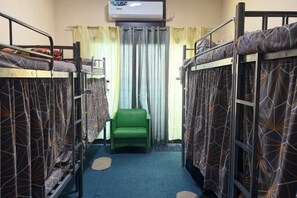 A room with bunk beds, a green chair, and an air conditioning unit. - Rovers Hostel (Dubai)
