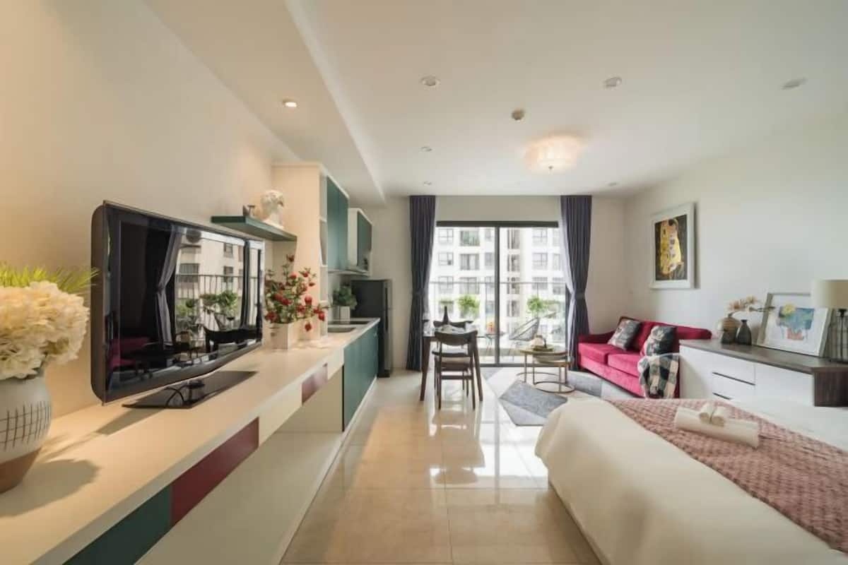 Ein modernes Hotelzimmer mit einem großen Bett, einem Fernseher, einem Essbereich und einem Balkon mit Blick auf die Stadt.