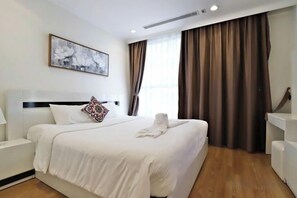 Une chambre d’hôtel avec un grand lit, une table de chevet, une commode, un bureau et une chaise.