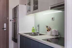 A kitchen with a stainless steel refrigerator, a sink, and a window above the counter.