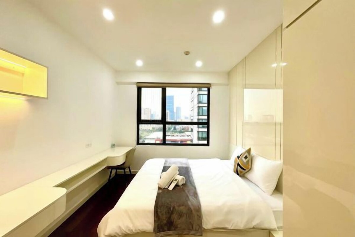 Ein Hotelzimmer mit Bett, Schreibtisch und Fenster mit Blick auf die Stadt.