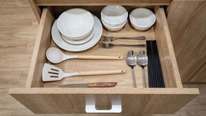 A drawer containing white bowls, plates, a knife, a spatula, a fork, a spoon, and a pair of chopsticks. - Hearth and Home Ben Thanh (5 mins to Ben Thanh Market) (Ho Chi Minh City)
