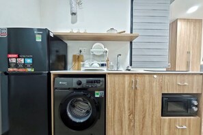 Cocina compacta con lavadora, microondas y refrigerador.