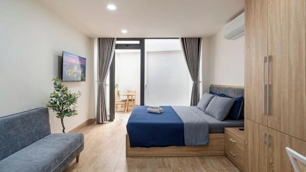 A bedroom with a bed, a sofa, a small table, a plant, and a wardrobe. - Hearth and Home Ben Thanh (5 mins to Ben Thanh Market) (Ho Chi Minh City)