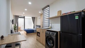 A compact kitchen with a washing machine, a refrigerator, and a dining area with a table and chairs. - Hearth and Home Ben Thanh (5 mins to Ben Thanh Market) (Ho Chi Minh City)
