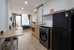 Ett kompakt kök med tvättmaskin, kylskåp och en matplats med bord och stolar.