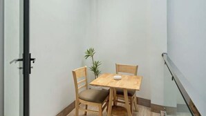 A corner room with a small wooden table and two chairs, a potted plant, and a glass door. - Hearth and Home Ben Thanh (5 mins to Ben Thanh Market) (Ho Chi Minh City)