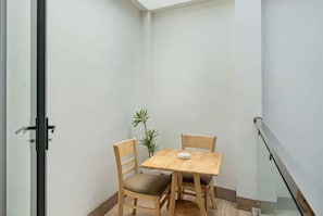 A corner room with a small wooden table and two chairs, a potted plant, and a glass door. - Hearth and Home Ben Thanh (5 mins to Ben Thanh Market) (Ho Chi Minh City)