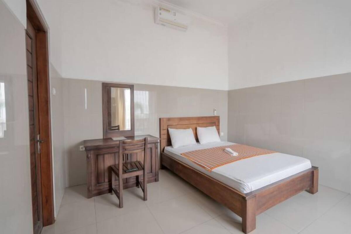 Un dormitorio con una cama de madera, un escritorio con silla y un espejo.