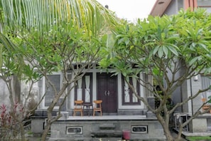 Un bâtiment traditionnel doté d’un porche, de deux chaises et d’un petit élément décoratif aquatique.