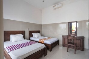 Une chambre d’hôtel avec deux lits, une coiffeuse avec un miroir et un sol carrelé.