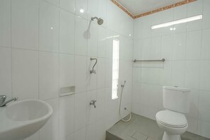 A bathroom with white tiles, a sink, a toilet, and a shower.