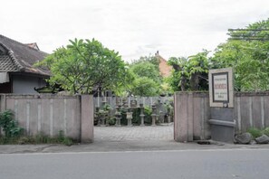 Una entrada con reja, un letrero, un camino pavimentado y un edificio con techo de tejas.