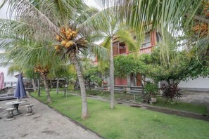 Un jardín con palmeras y un edificio de fachada roja.
