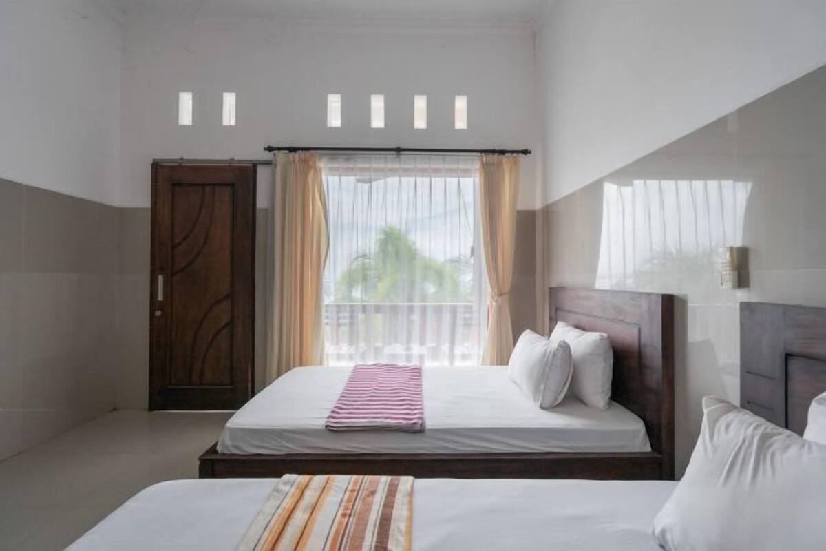 Una habitación de hotel con una cama grande, un armario de madera y una ventana con cortinas.