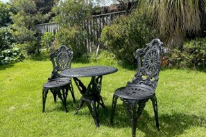 A round metal table with four chairs in a grassy outdoor area. - Garden View Entire Self Contained Guesthouse (Engadine)