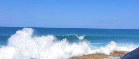 Une côte rocheuse où les vagues s’écrasent contre les rochers.
