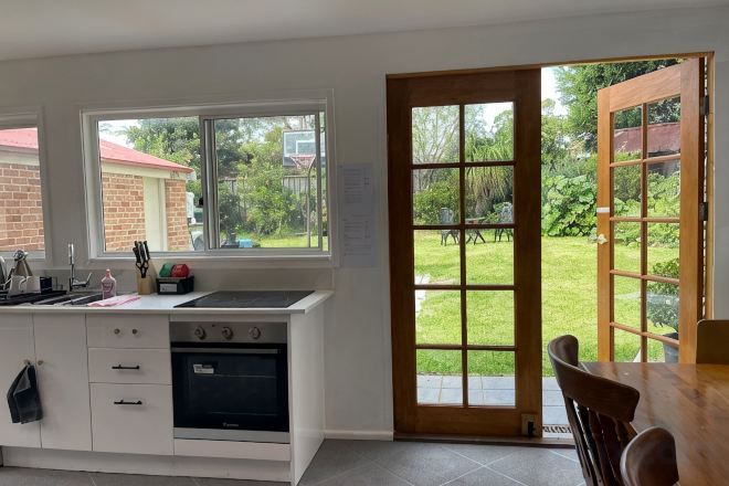 Una cocina con horno integrado, un lavamanos y una ventana con vistas a un jardín.