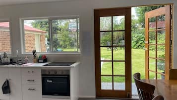 Una cocina con horno integrado, un lavamanos y una ventana con vistas a un jardín.