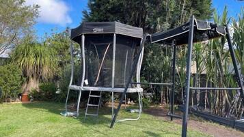 A trampoline with a safety net enclosure in a grassy yard.