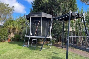 A trampoline with a safety net enclosure in a grassy yard. - Garden View Entire Self Contained Guesthouse (Engadine)