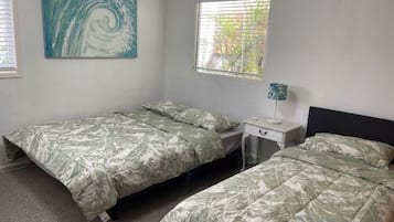Un dormitorio con dos camas individuales, una mesita de noche, una lámpara y un cuadro en la pared.