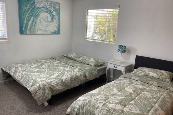 A bedroom with two single beds, a nightstand, a lamp, and a painting on the wall. - Garden View Entire Self Contained Guesthouse (Engadine)