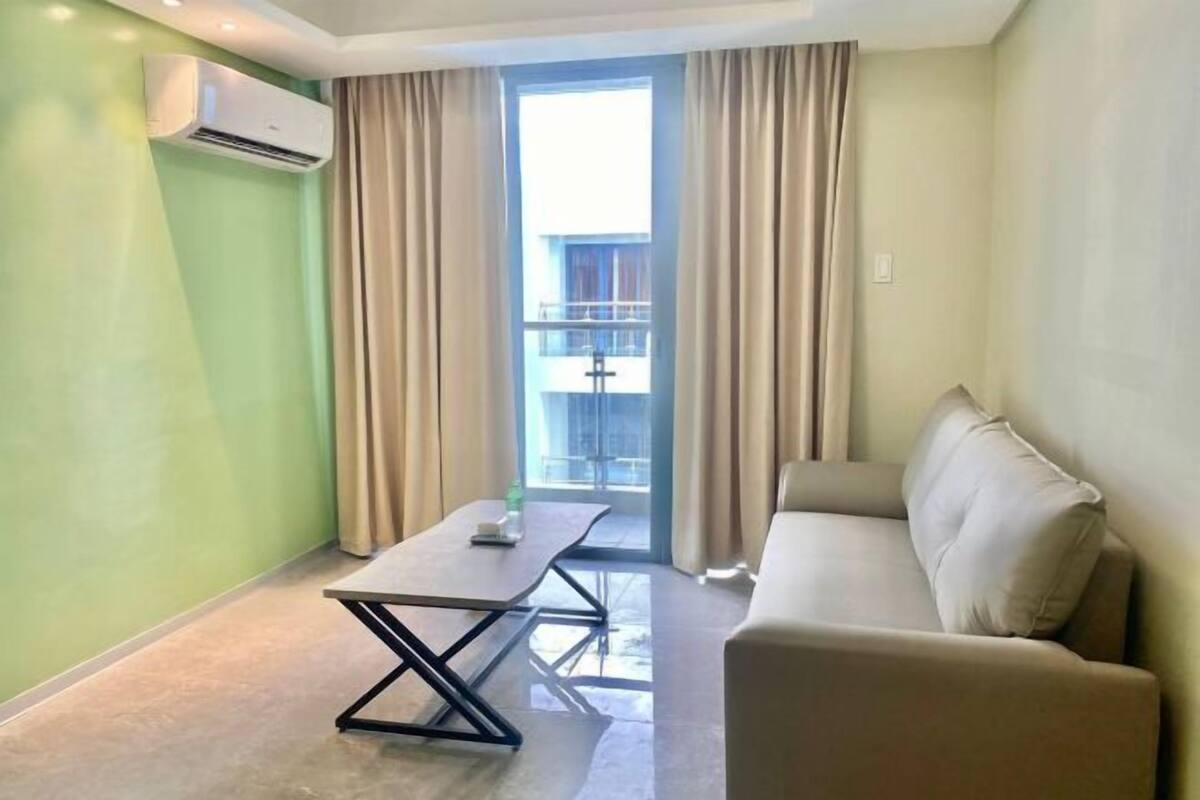 Una habitación moderna con sofá, mesa y ventana con cortinas.