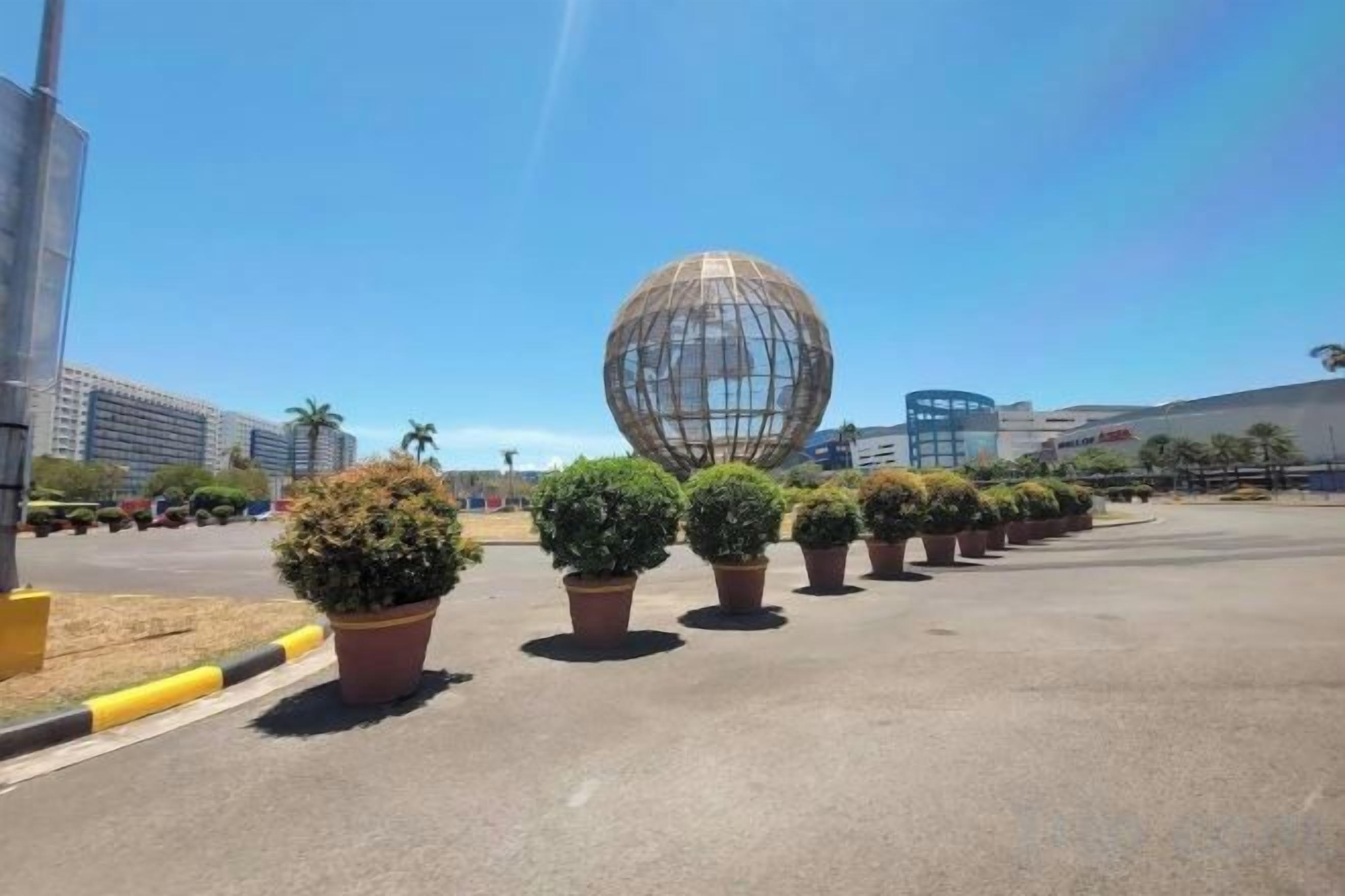A parking lot with potted plants and a large spherical structure.