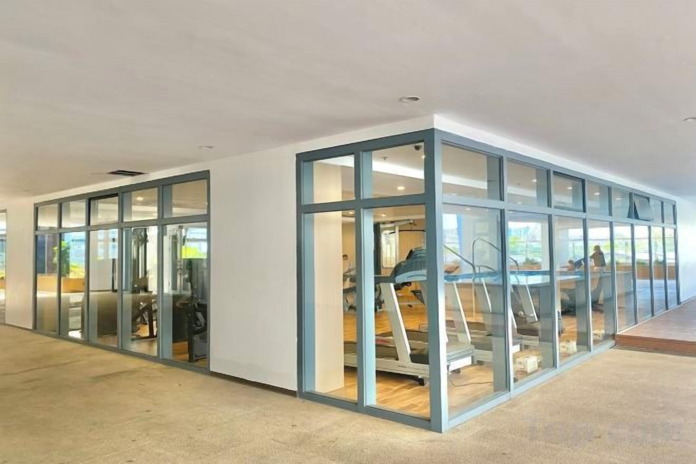 A modern interior with glass partitions, a visible treadmill, and a staircase.