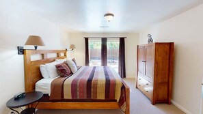 Een slaapkamer met een bed, nachtkastje, lamp, kledingkast en uitzicht door een raam.