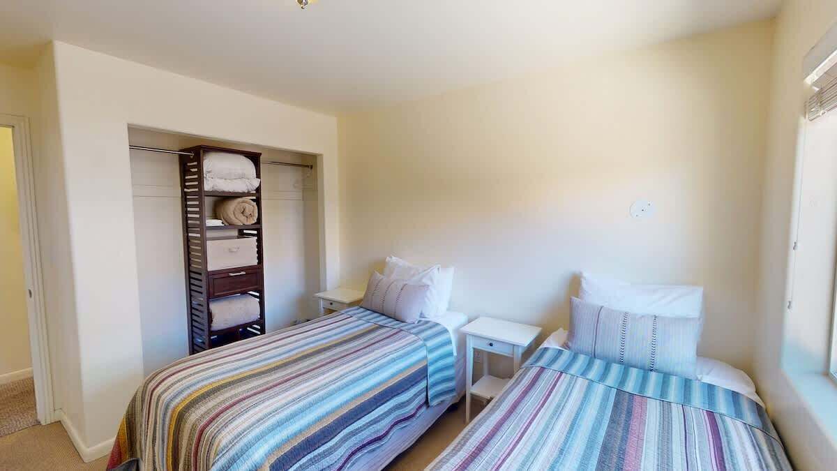A bedroom with two beds, a wardrobe, and a nightstand.