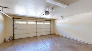 Eine Garage mit geschlossenem Garagentor, einer Deckenleuchte und einem Fenster.