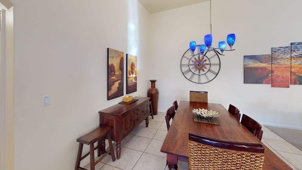 Un comedor con una mesa de madera, sillas, un florero y decoración en la pared.