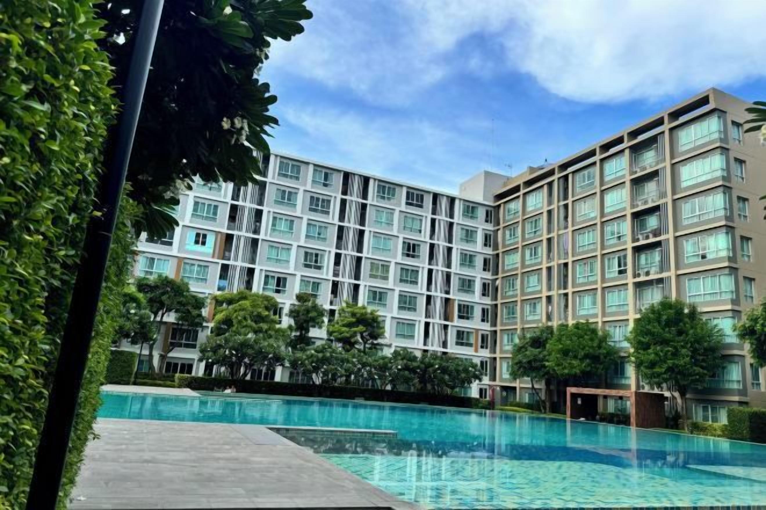Un hotel con piscina, varias plantas y un cielo despejado.