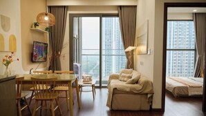 A modern living room with a sofa, dining table, chairs, and a lamp. - A Quiet Stay - Service Apartment, Vinhome Ocean Park, Ha Noi (Hanoi)