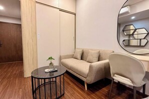 A modern living room with a sofa, a round table, a chair, and a mirror. - A Quiet Stay - Service Apartment, Vinhome Ocean Park, Ha Noi (Hanoi)