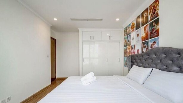 A bedroom with a large bed, a wardrobe, and a wall decorated with movie posters. - The Landmark Platinum - Vinhomes Central Park (Ho Chi Minh City)