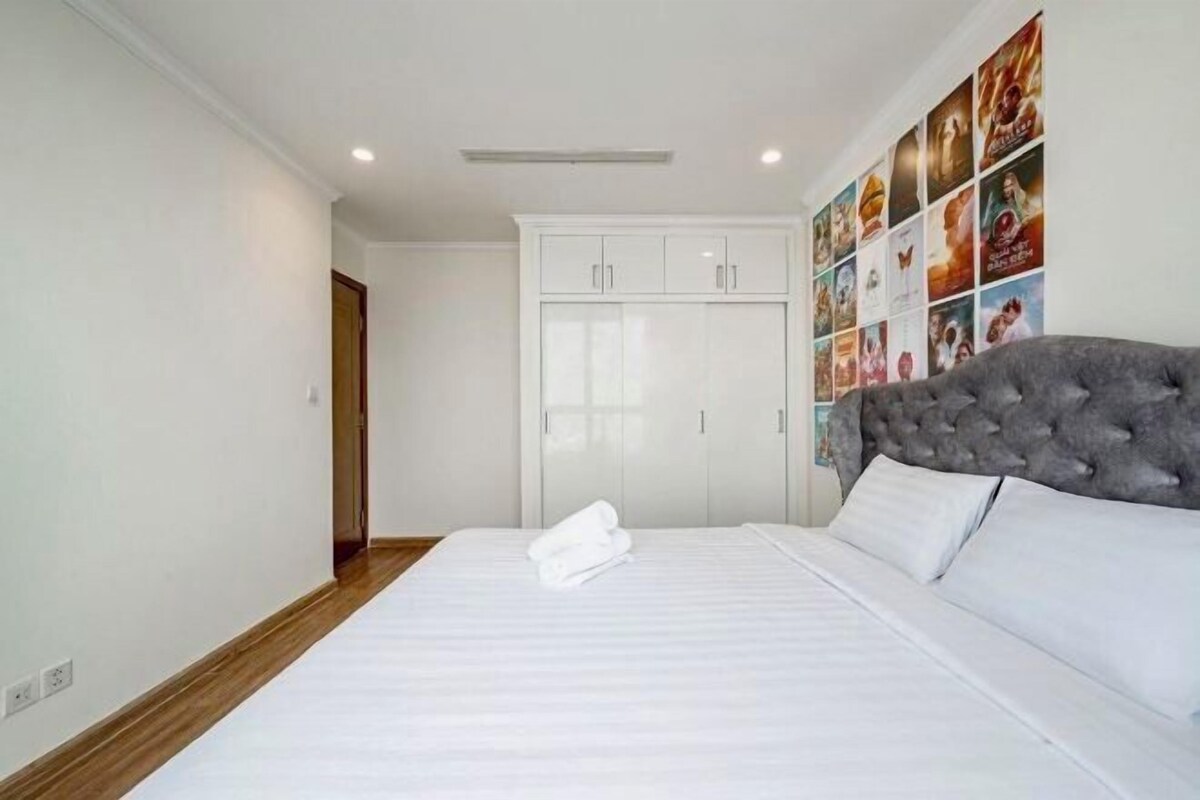 A bedroom with a large bed, a wardrobe, and a wall decorated with movie posters.